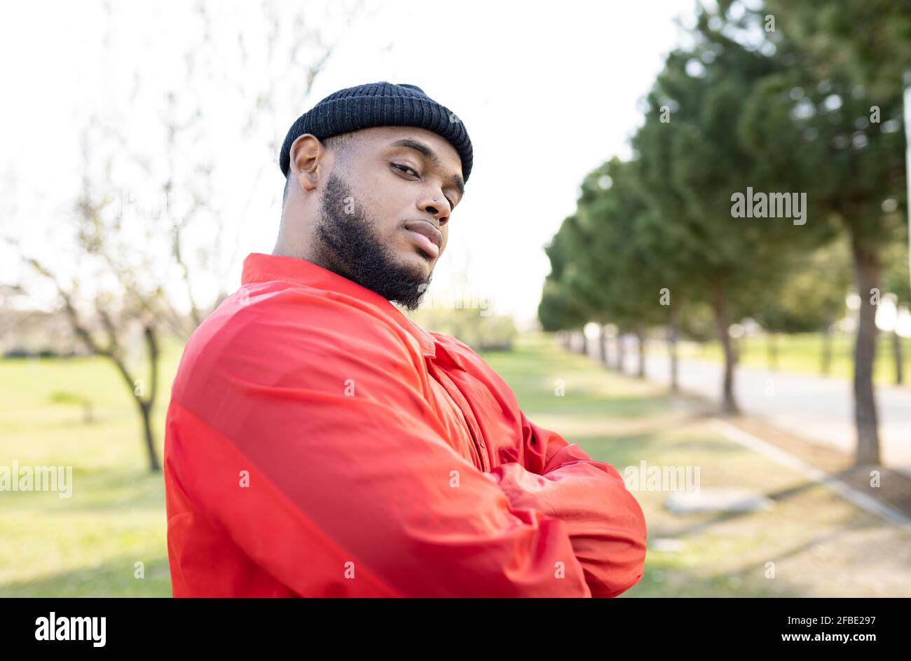 Schöner Mann mit gekreuzten Armen, der im Park steht Stockfoto