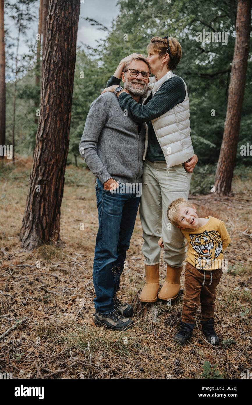 Frau küsst Mann, während mit Jungen im Wald stehen während Urlaub Stockfoto