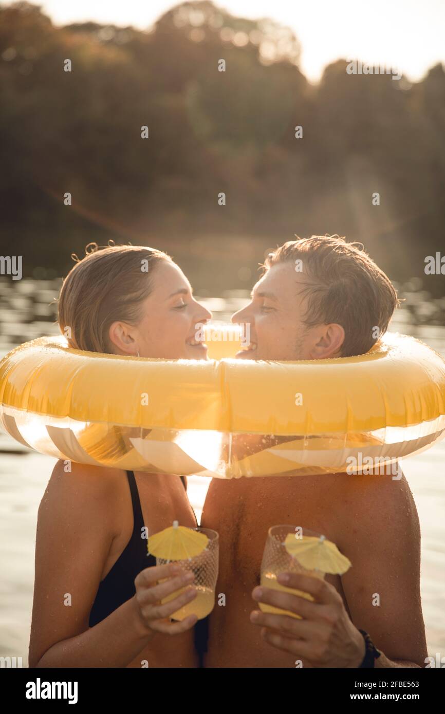 Junges Paar mit Getränk Sonnenschirme in ihrem Haar, Spaß am See Stockfoto