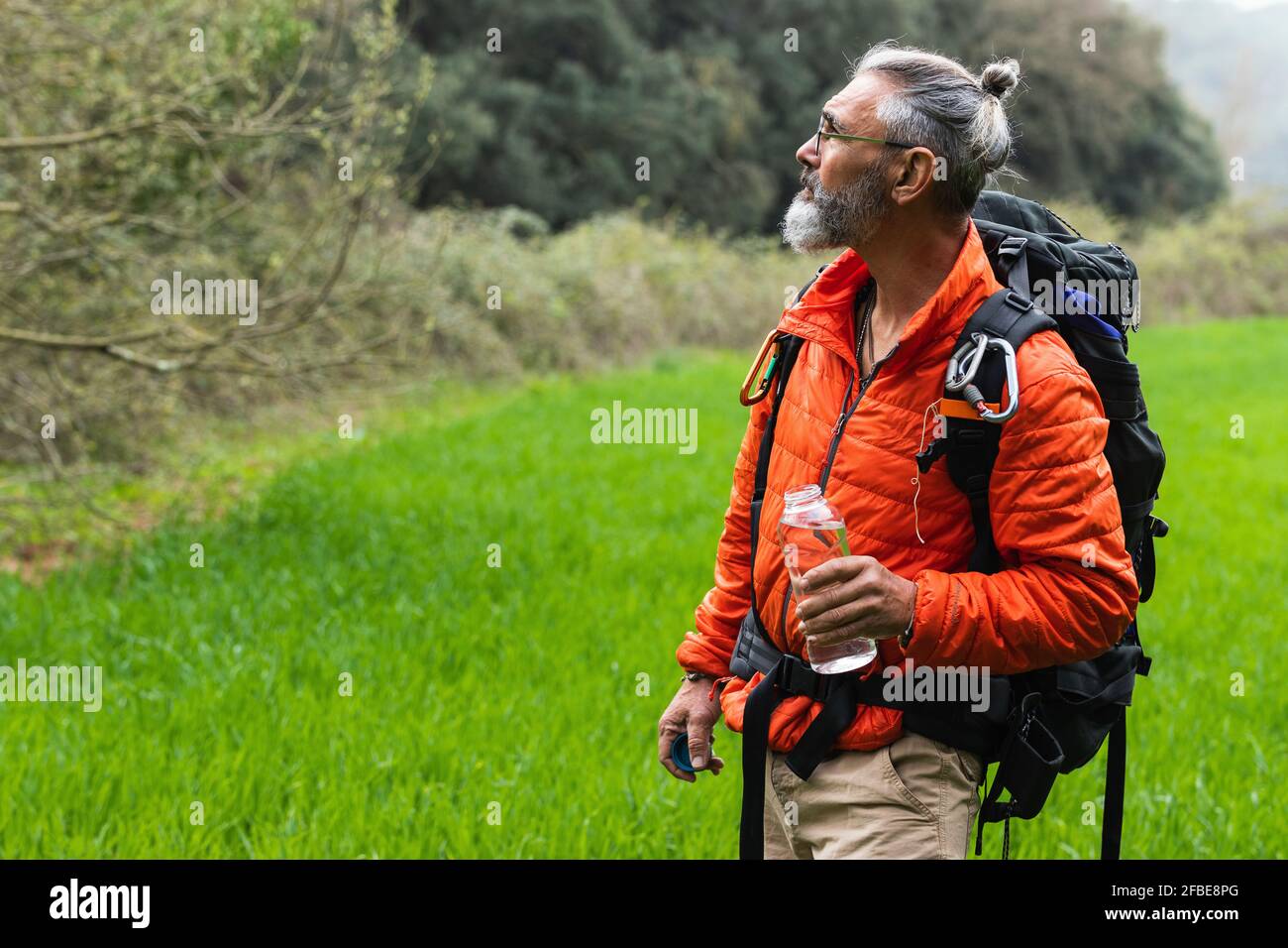 Älterer männlicher Entdecker mit Rucksack und Wasserflasche, der wegschaut Am Wochenende Stockfoto