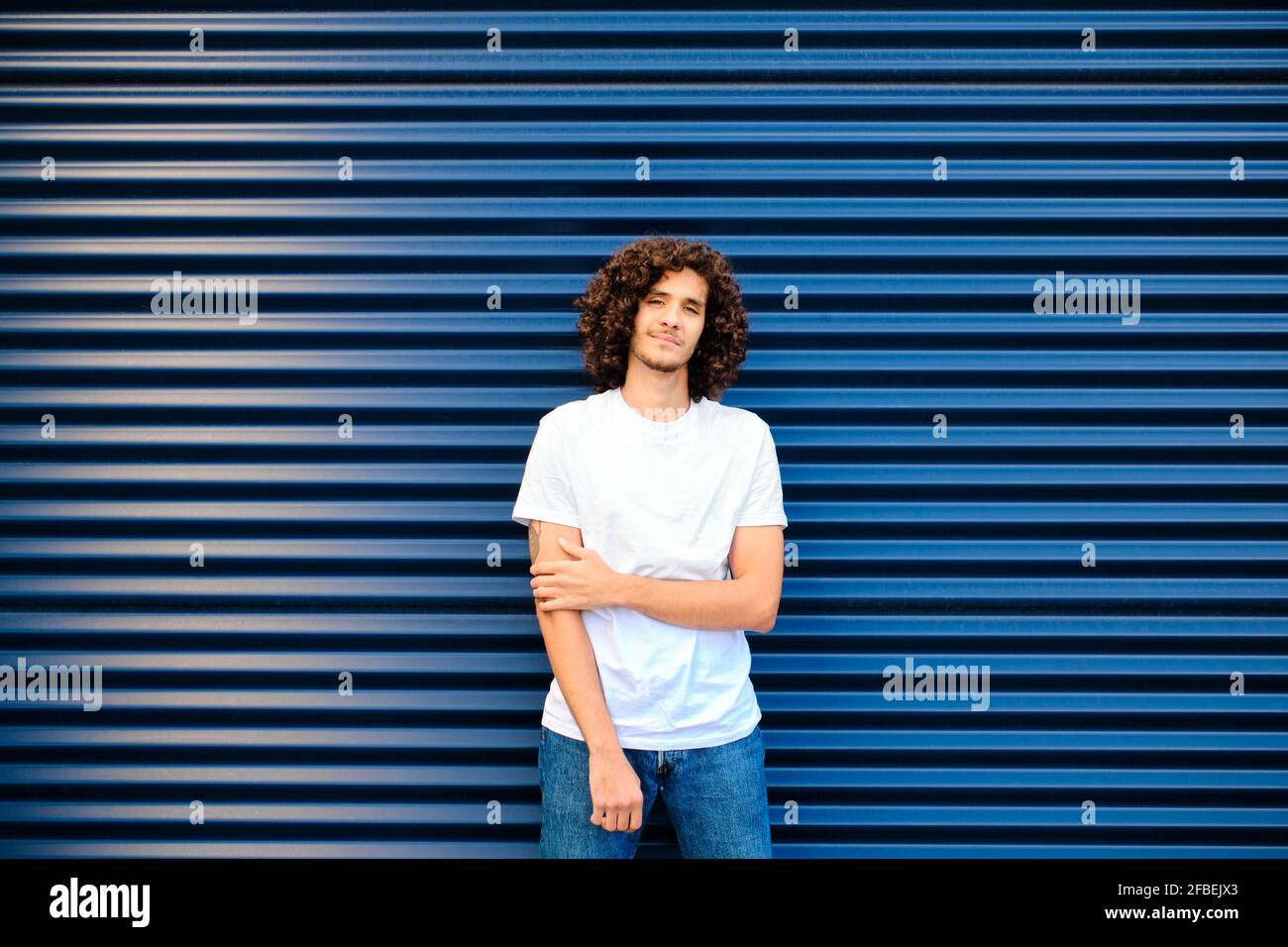 Kaukasischer junger Mann, der vor einem blauen Verschluss steht Stockfoto