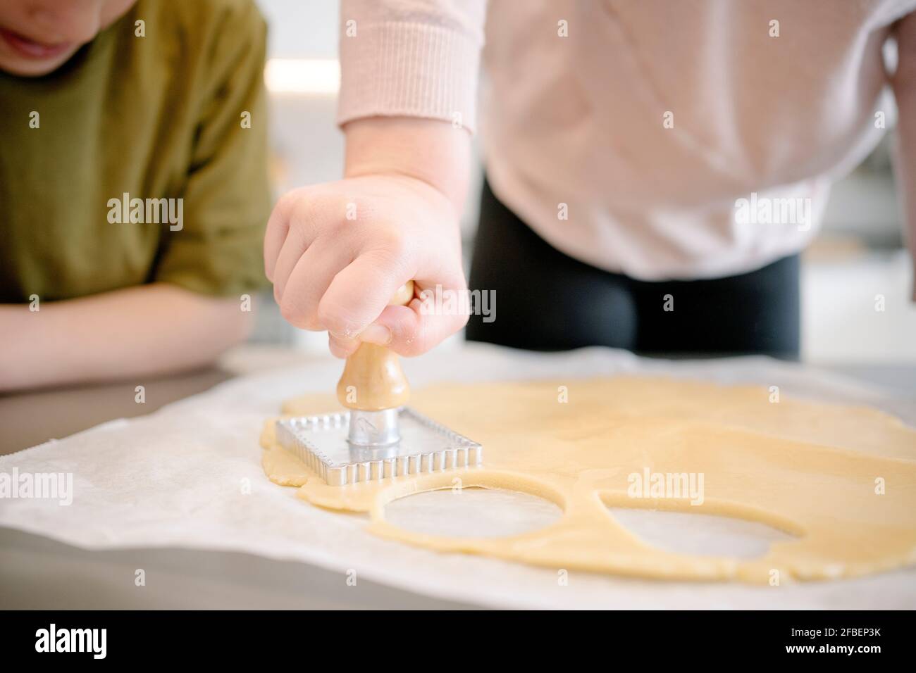 Mädchen mit Holzgriff Ausstechform auf Teig in der Küche Während Sie es betrachten Stockfoto