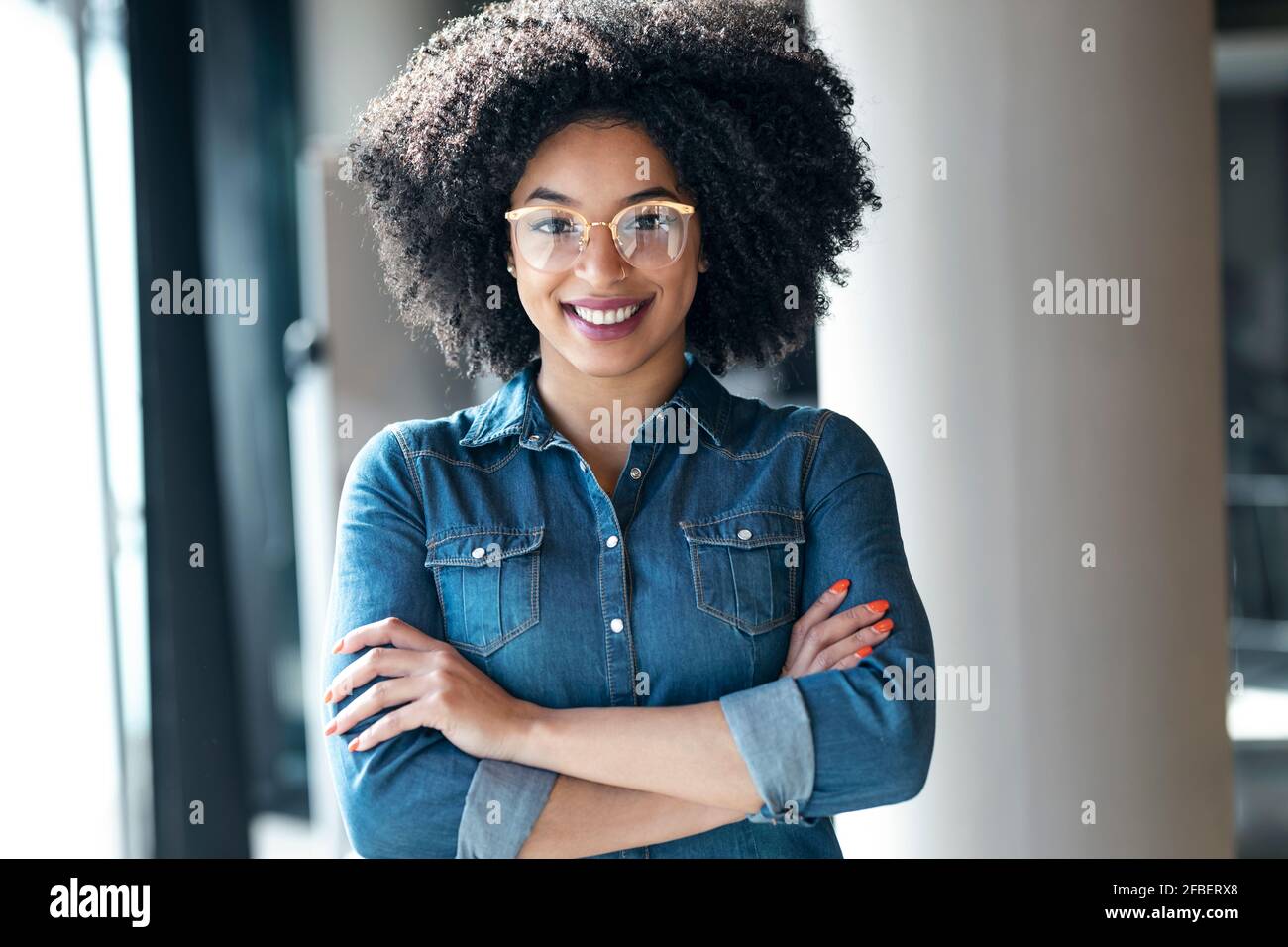 Junge Geschäftsfrau mit verschränkten Armen lächelnd Stockfoto