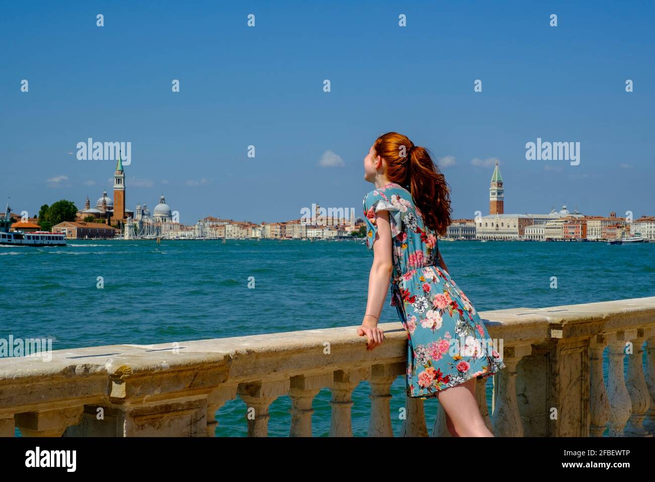 Junge Frau, die sich an sonnigen Tagen auf Baluster stützt Stockfoto