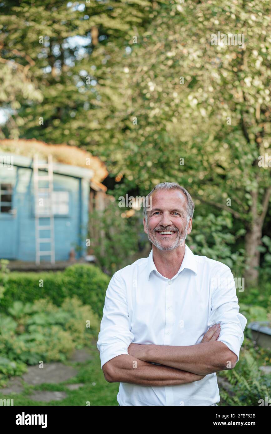 Reifer Mann mit gekreuzten Armen, der im Garten steht Stockfoto