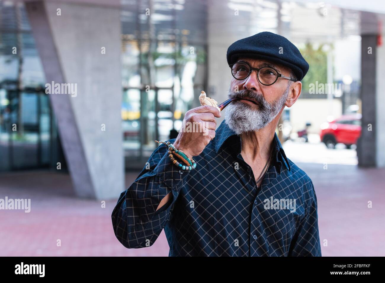 Ernsthafter Tag des Mannes, der träumt, während er in der Stadt Pfeife hält Stockfoto