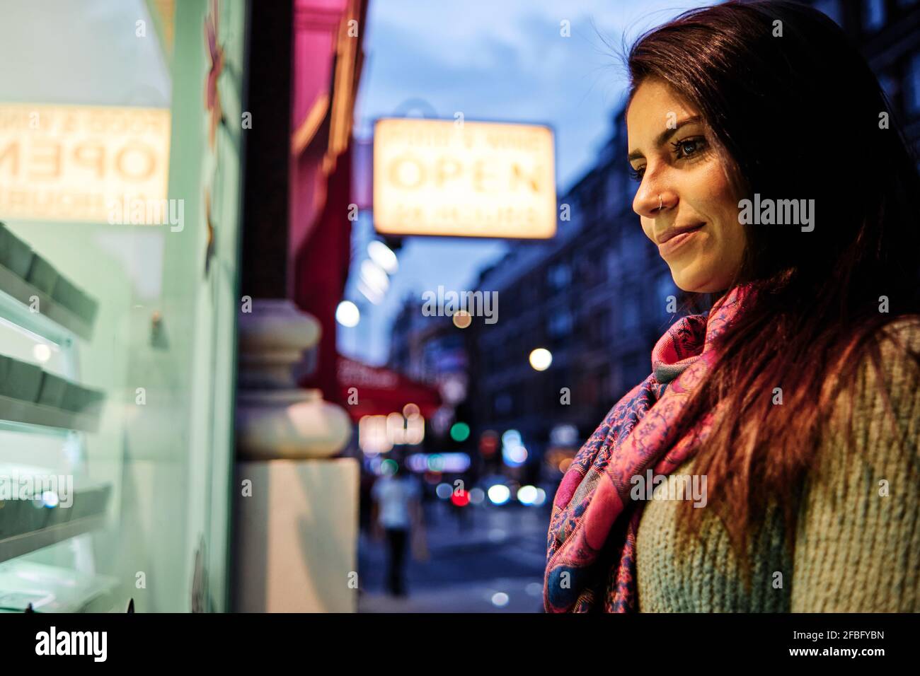 Lächelnde Frau, die auf das Ladendisplay in der Stadt schaut Stockfoto