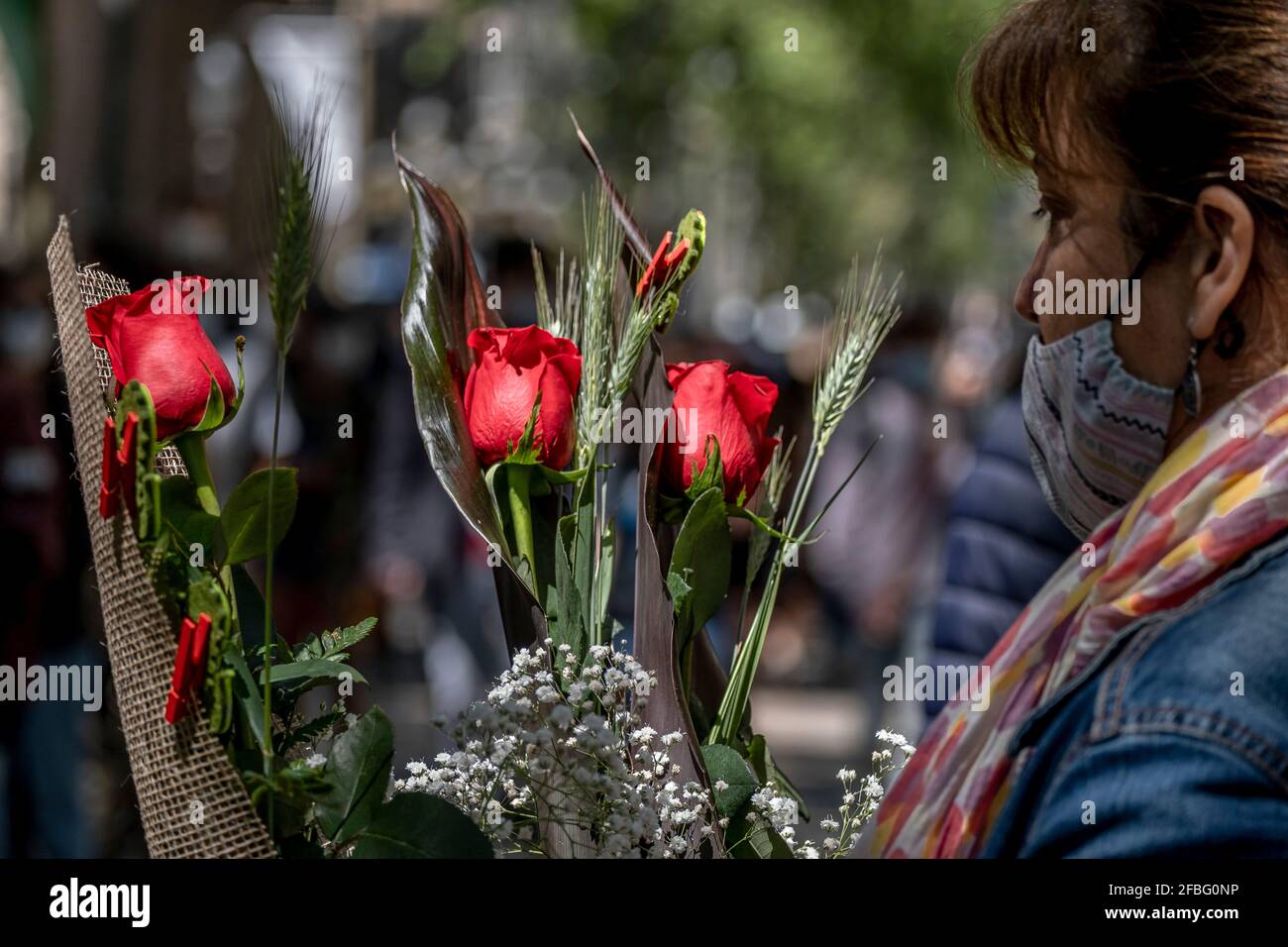 Barcelona, Spanien. April 2021. Eine Frau wird vor einem der traditionellen Blumenläden auf den Ramblas in Barcelona beim Kauf roter Rosen gesehen.Trotz der Kapazitätskontrolle und der Distanzierungsmaßnahmen aufgrund der Covid-Pandemie gewinnt Barcelona erfolgreich das Fest von Sant Jordi, der schutzpatronin von Katalonien, Mit dem traditionellen Tag des Verkaufs von Büchern und Rosen. (Foto von Paco Freire/SOPA Images/Sipa USA) Quelle: SIPA USA/Alamy Live News Stockfoto