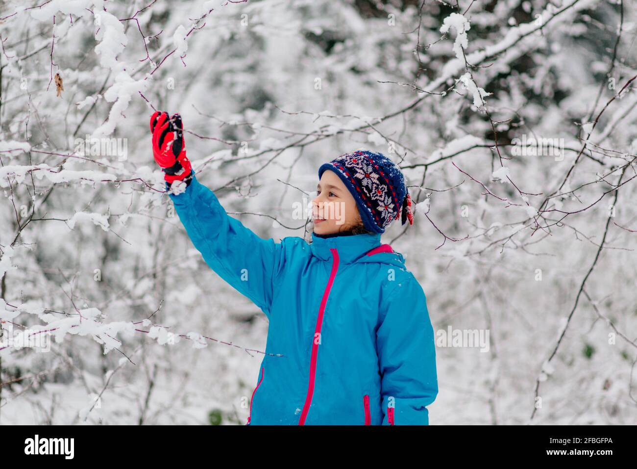 Mädchen, das in einem winterlichen Wald steht Stockfoto