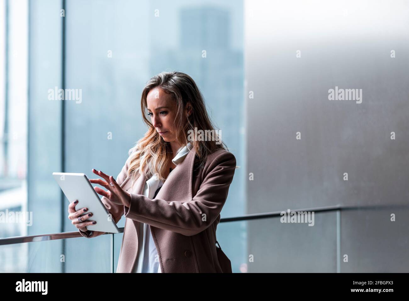 Konzentrierte Geschäftsfrau mit digitalem Tablet durch Geländer Stockfoto