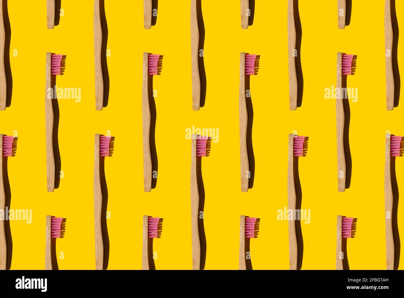 Digital generiertes Muster mit Bambus-Zahnbürsten auf gelbem Hintergrund Stockfoto