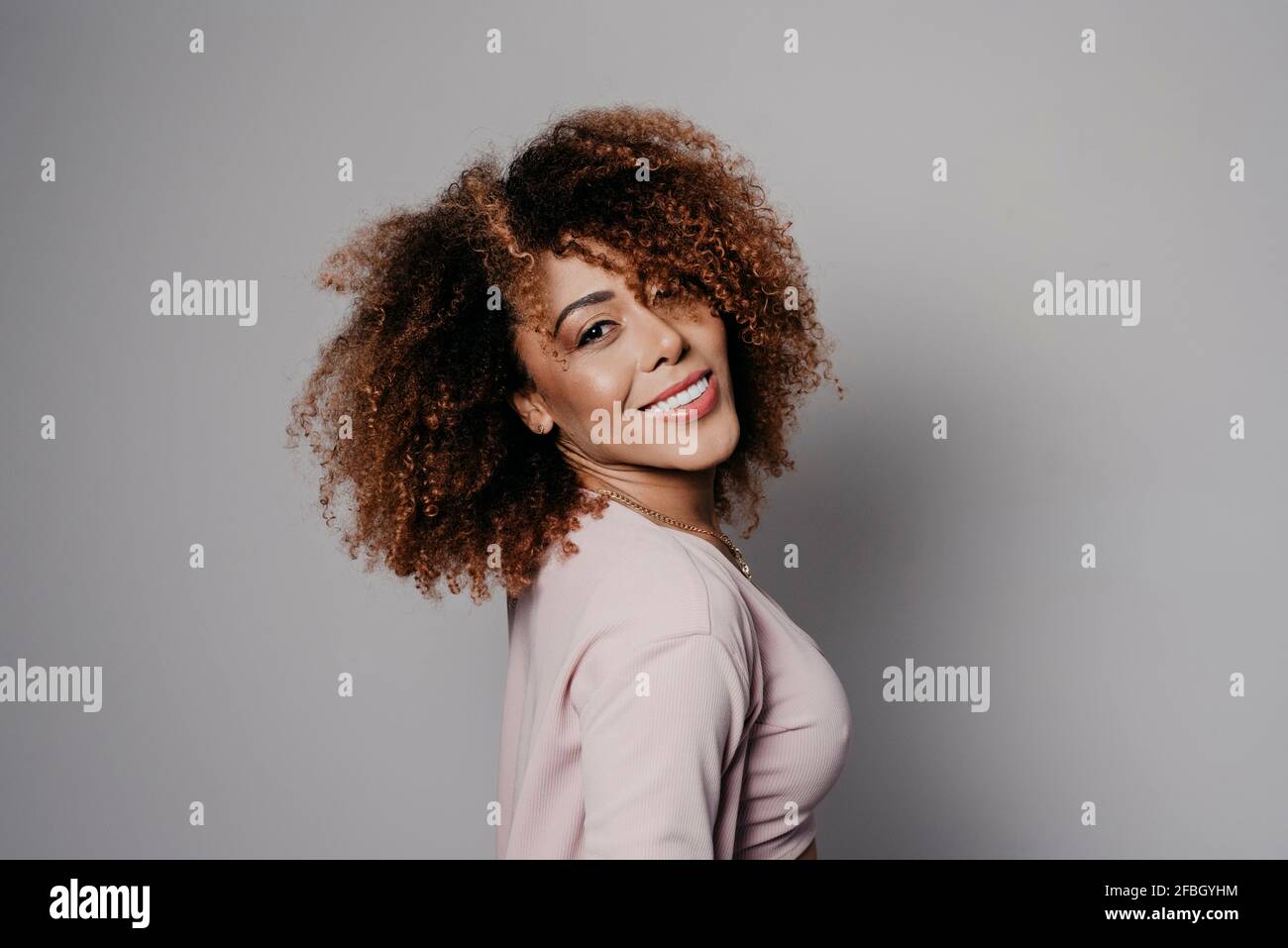 Lächelnde junge attraktive Frau vor grauem Hintergrund Stockfoto