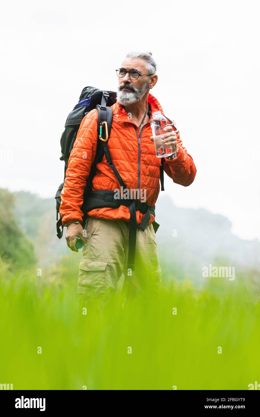 Männlicher Entdecker schaut weg, während er am Wochenende eine Wasserflasche hält Stockfoto