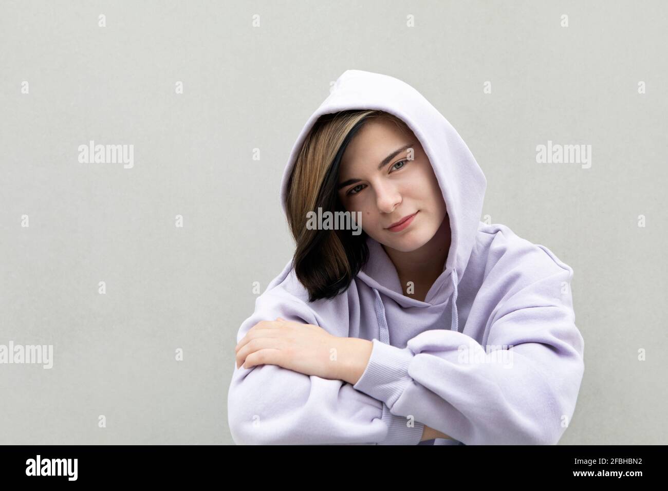 Schönes Mädchen in lila Kapuzenhemd von grauen Wand Stockfoto