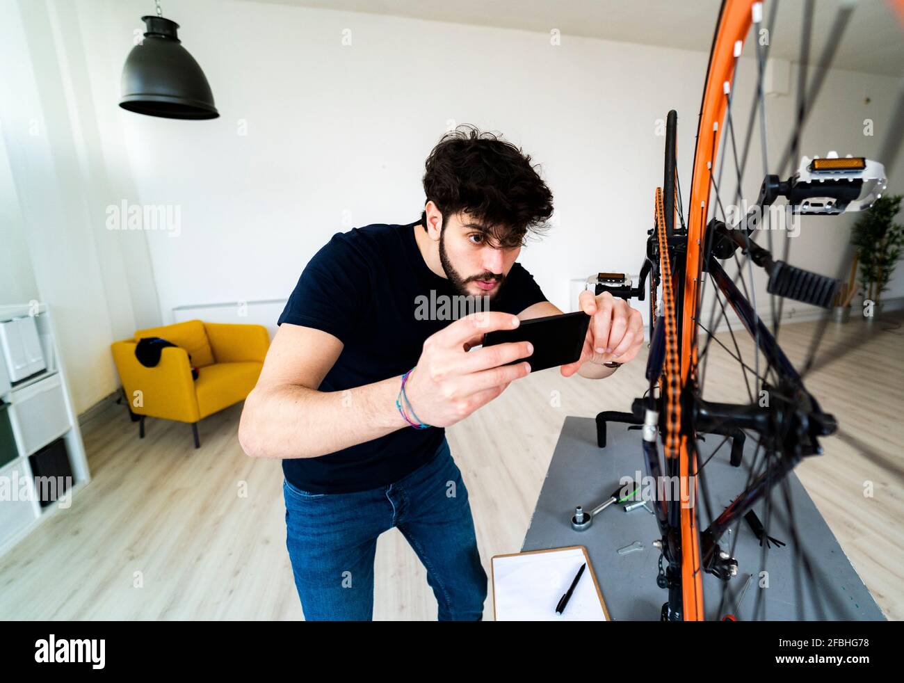 Mann fotografiert Fahrradteile über Smartphone zu Hause Stockfoto