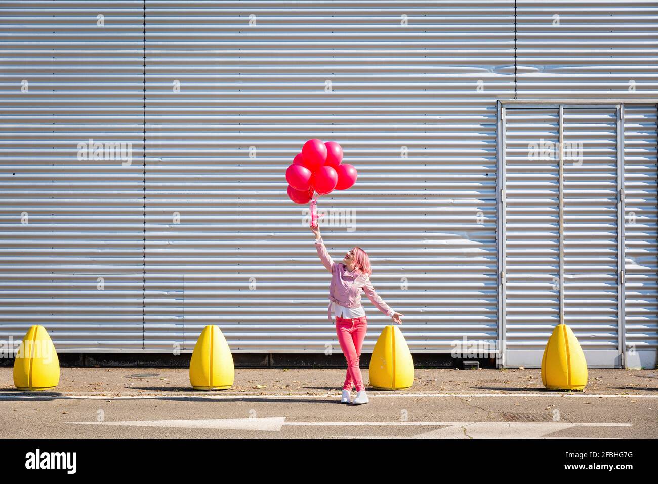 Frau in rosa Jacke Blick auf Ballons auf der Straße Stockfoto