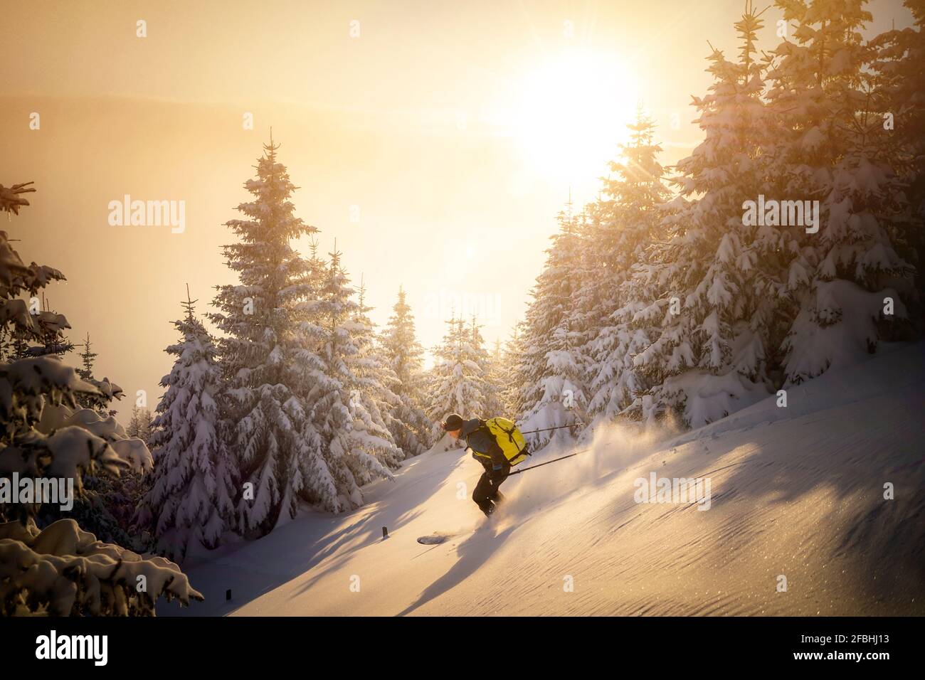 Mittelalter Mann, der während des Sonnenaufgangs auf einem verschneiten Berg Ski fährt Stockfoto