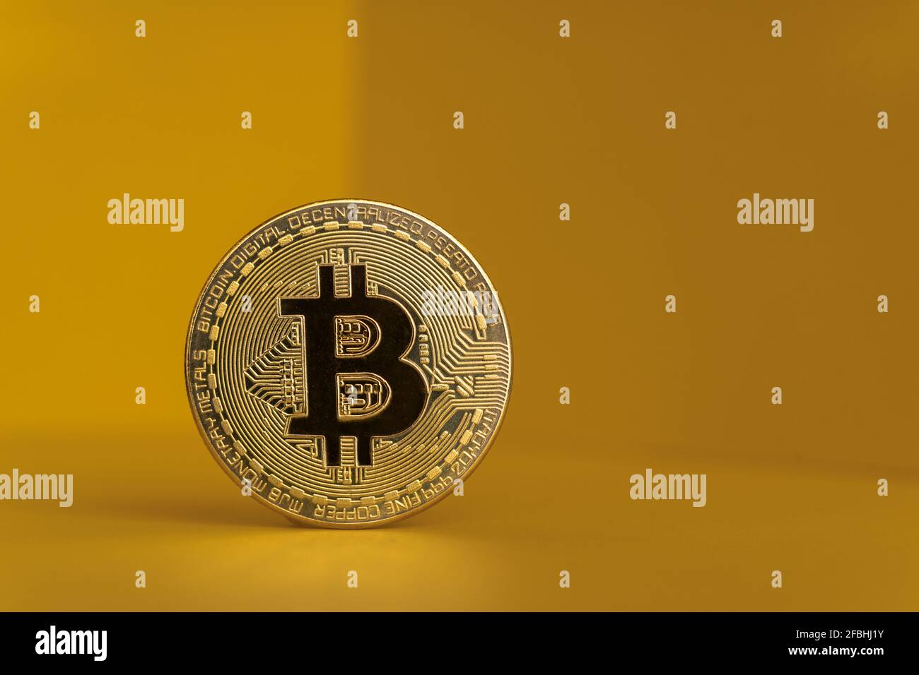 Goldfarbenes Bitcoin vor gelbem Hintergrund Stockfoto