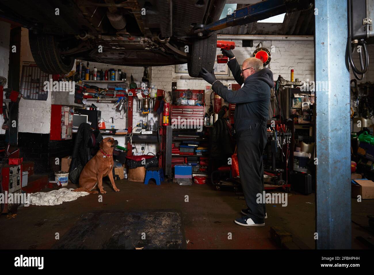 Leitender männlicher Mechaniker, der Reifen in der Garage ersetzt Stockfoto