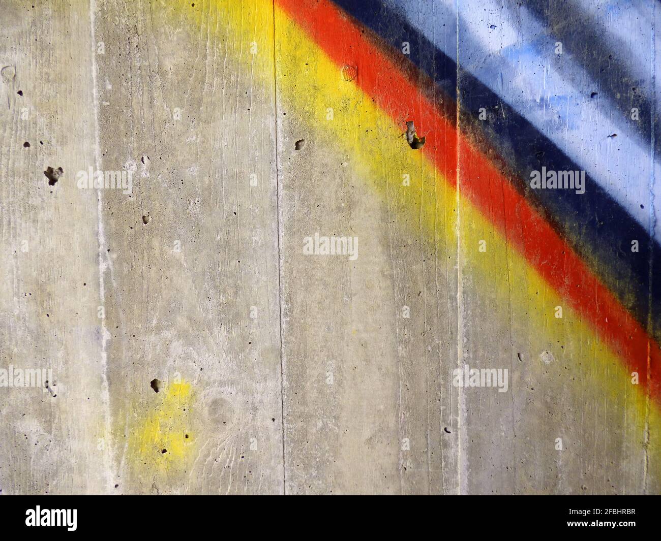 Gelb, rot, blau, weiß und schwarz gesprüht in diagonalen Streifen auf einer grauen Betonwand Stockfoto Gelb, rot, blau, weiß und schwarz gesprüht in diagonalen Streifen auf einer grauen Betonwand Stockfoto