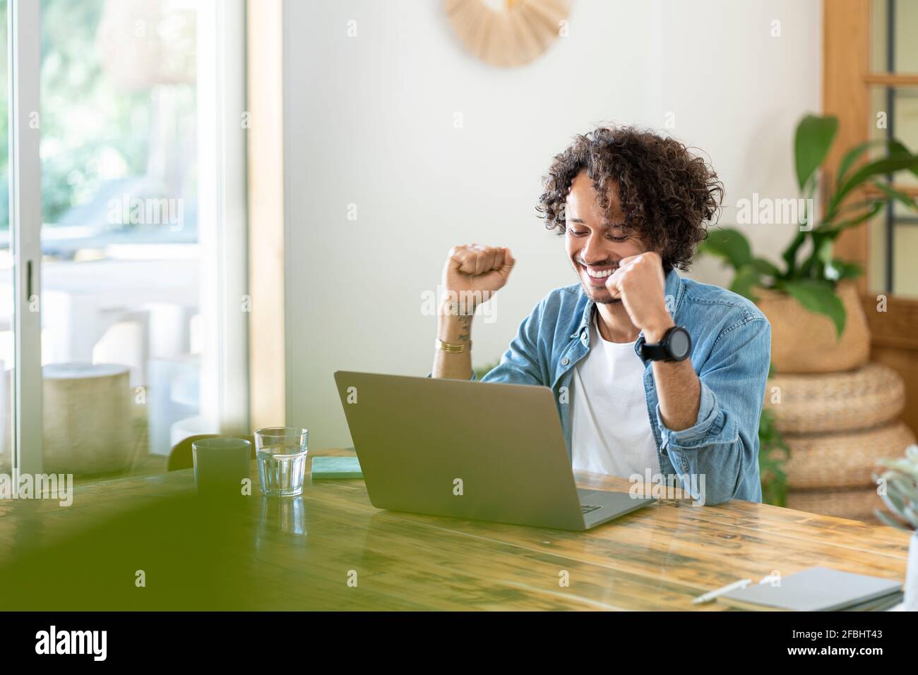 Ekstatischer männlicher Profi feiert Erfolg vor dem Laptop bei Zu Hause Stockfoto
