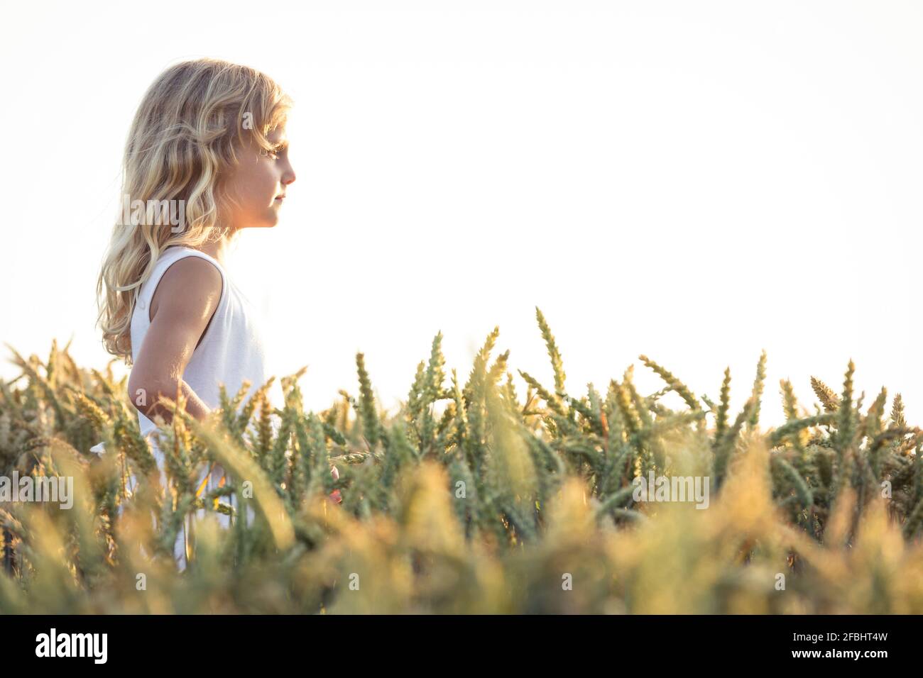 Blonde Mädchen Tag träumen, während auf landwirtschaftlichen Feld am Himmel stehen Stockfoto