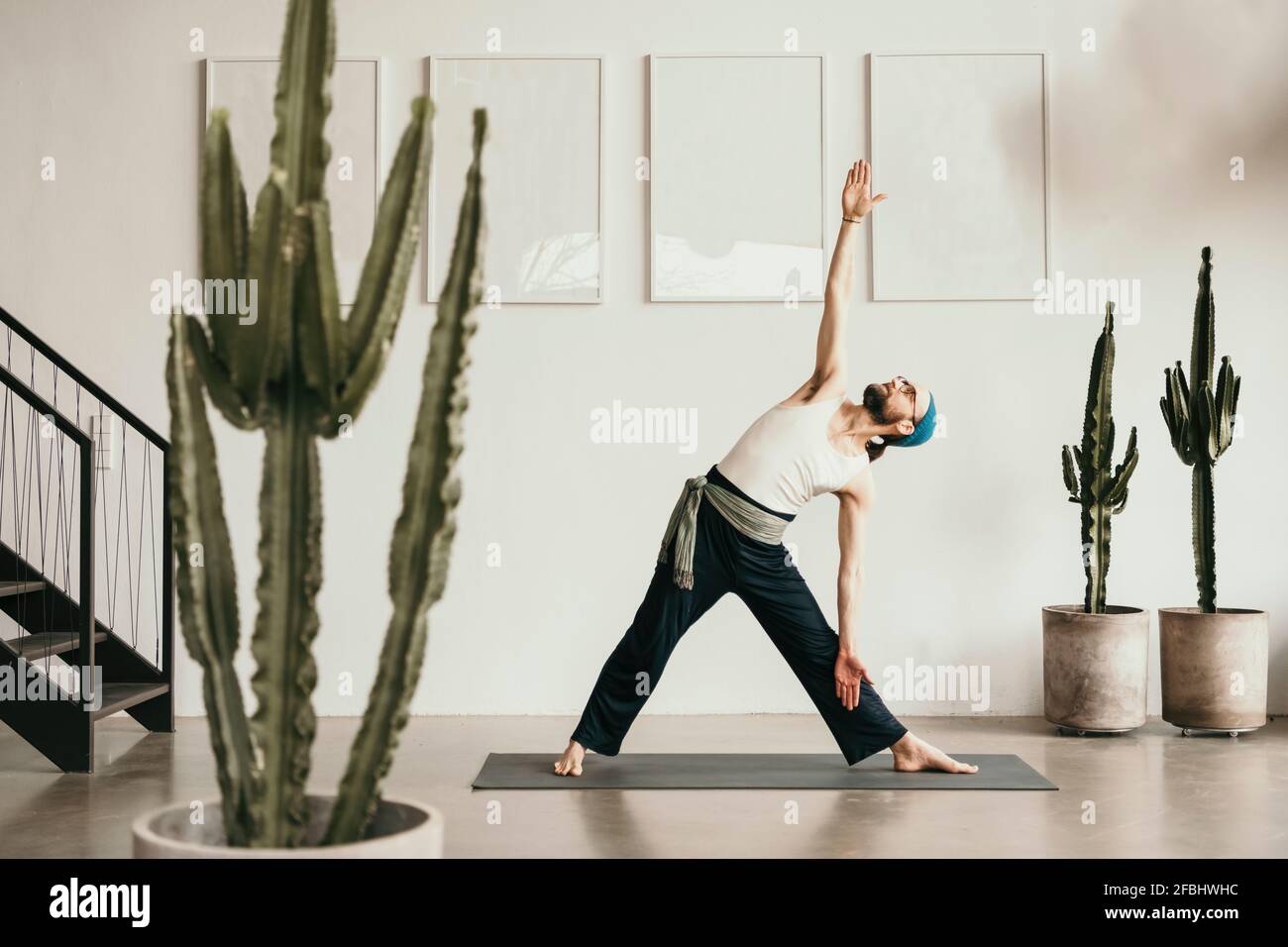 Männlicher Fitnesstrainer, der Yoga auf einer Trainingsmatte praktiziert Stockfoto