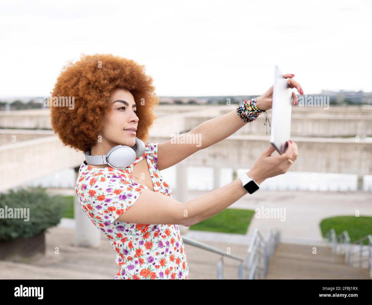 Frau mit Afro-Frisur nimmt Selfie durch digitales Tablet bei parken Stockfoto