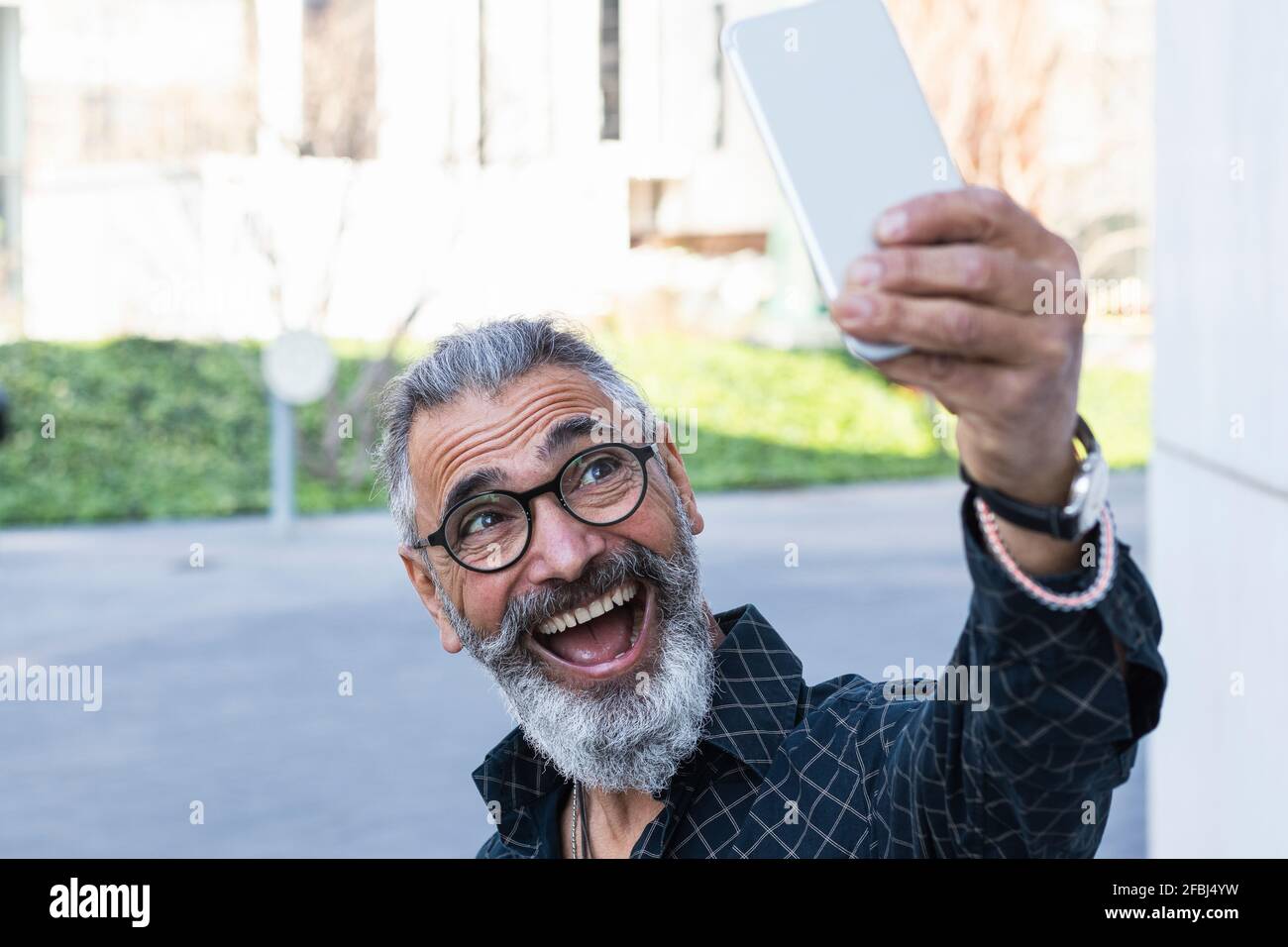 Fröhlicher Mann, der Selfie über das Mobiltelefon auf dem Fußweg gemacht hat Stockfoto
