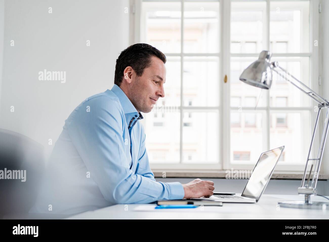 Männlicher Unternehmer, der am Arbeitsplatz einen Laptop verwendet Stockfoto