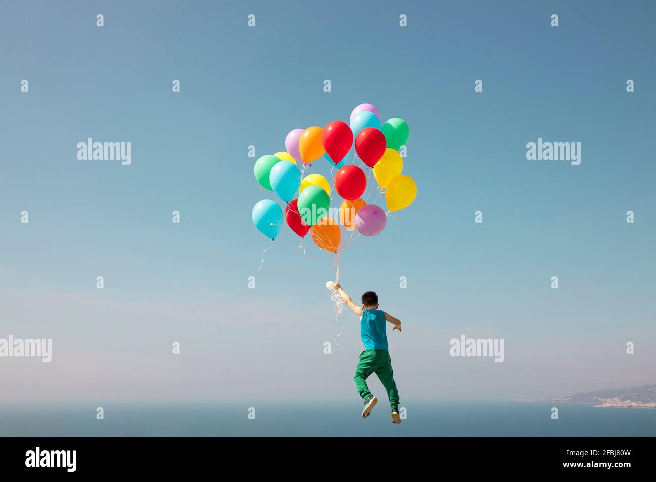 Junge, der mit einem Haufen Ballons am Himmel fliegt Stockfoto