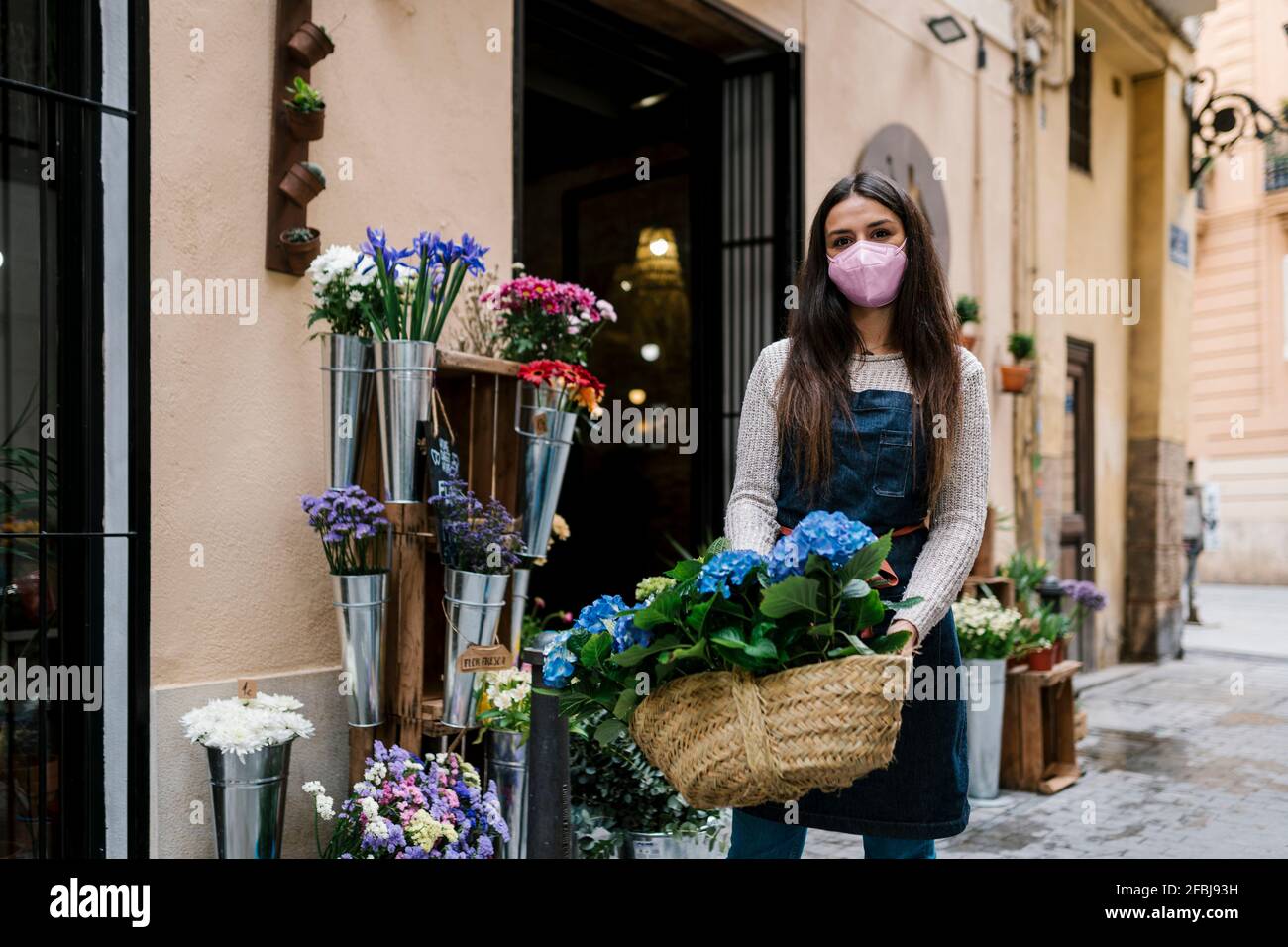 Junge Frau mit Hortensia-Blumenkorb im Geschäft Stockfoto