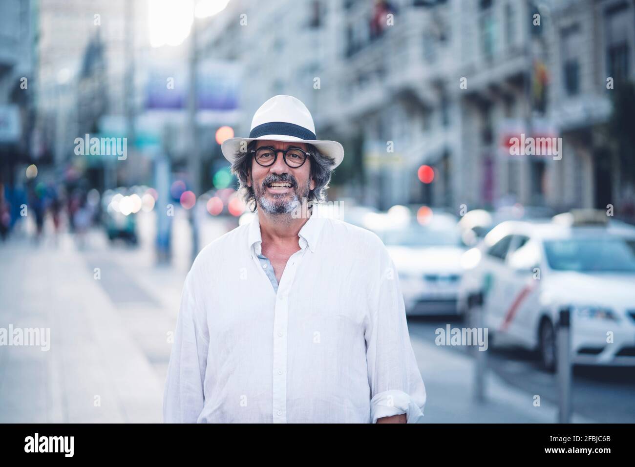 Porträt eines attraktiven älteren Mannes mit weißer Kleidung und Hut Posiert vor der Kamera in der Straße von Madrid Stockfoto