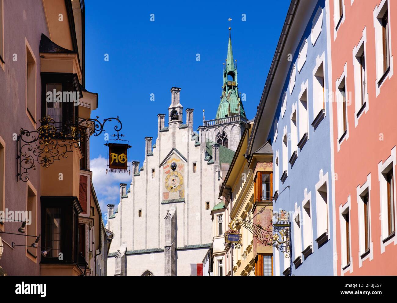 Franz-Josef-Straße mit Zunftschildern und Pfarrkirche im Hintergrund, Schwaz, Tirol, Österreich Stockfoto