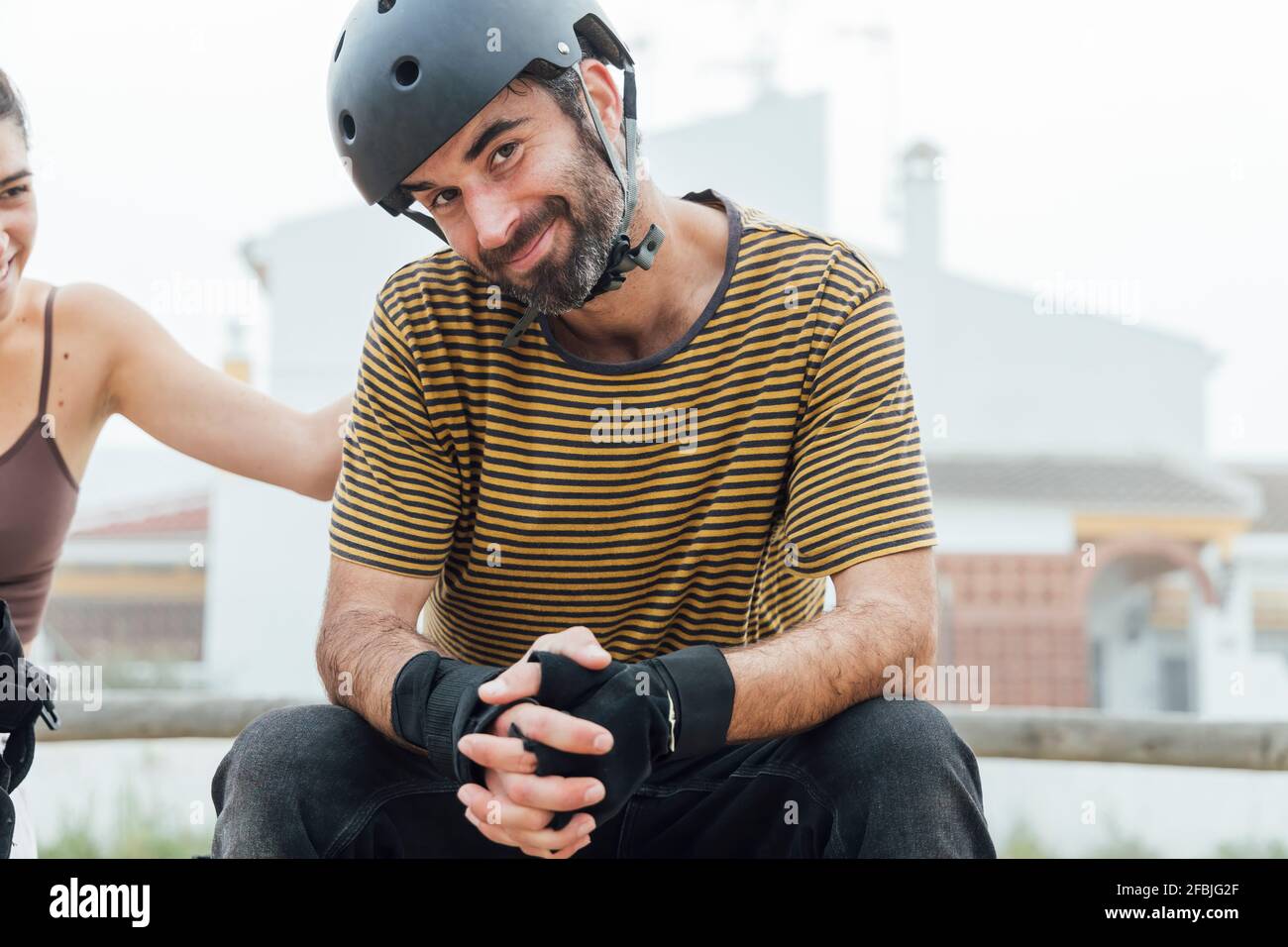 Ein erwachsener Mann mit Schutzhelm lächelt, während er neben einer Frau sitzt Stockfoto
