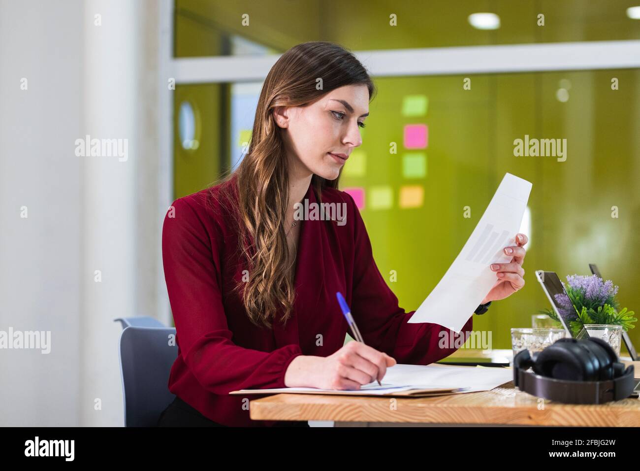 Geschäftsfrau prüft Dokument während der Arbeit am Arbeitsplatz Stockfoto