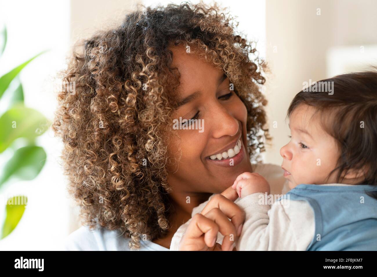Glückliche Mutter lächelt ihr niedliches Baby zu Hause an Stockfoto
