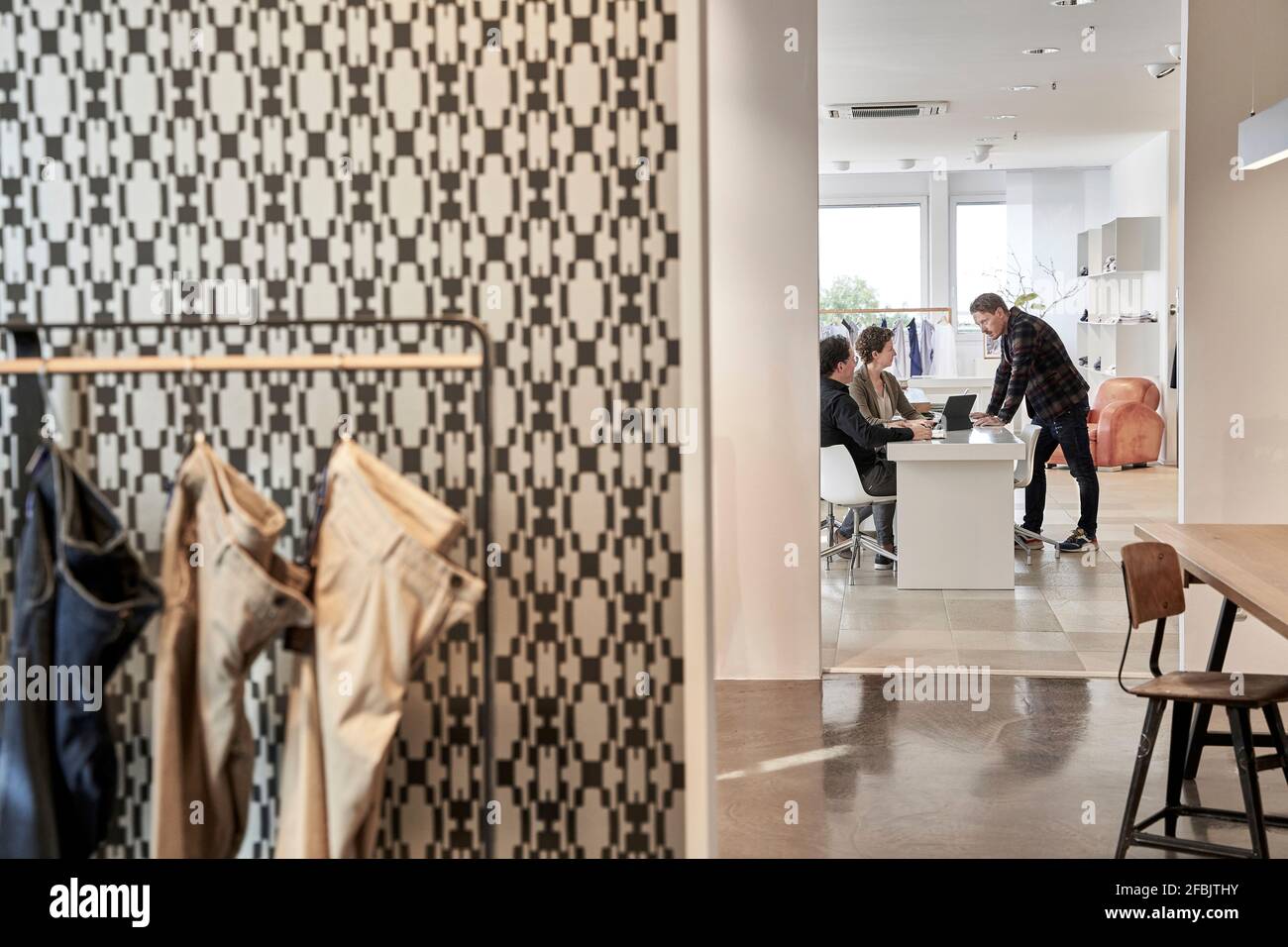 Der Besitzer diskutiert mit den Kunden am Schreibtisch im Bekleidungsdesign-Studio Stockfoto