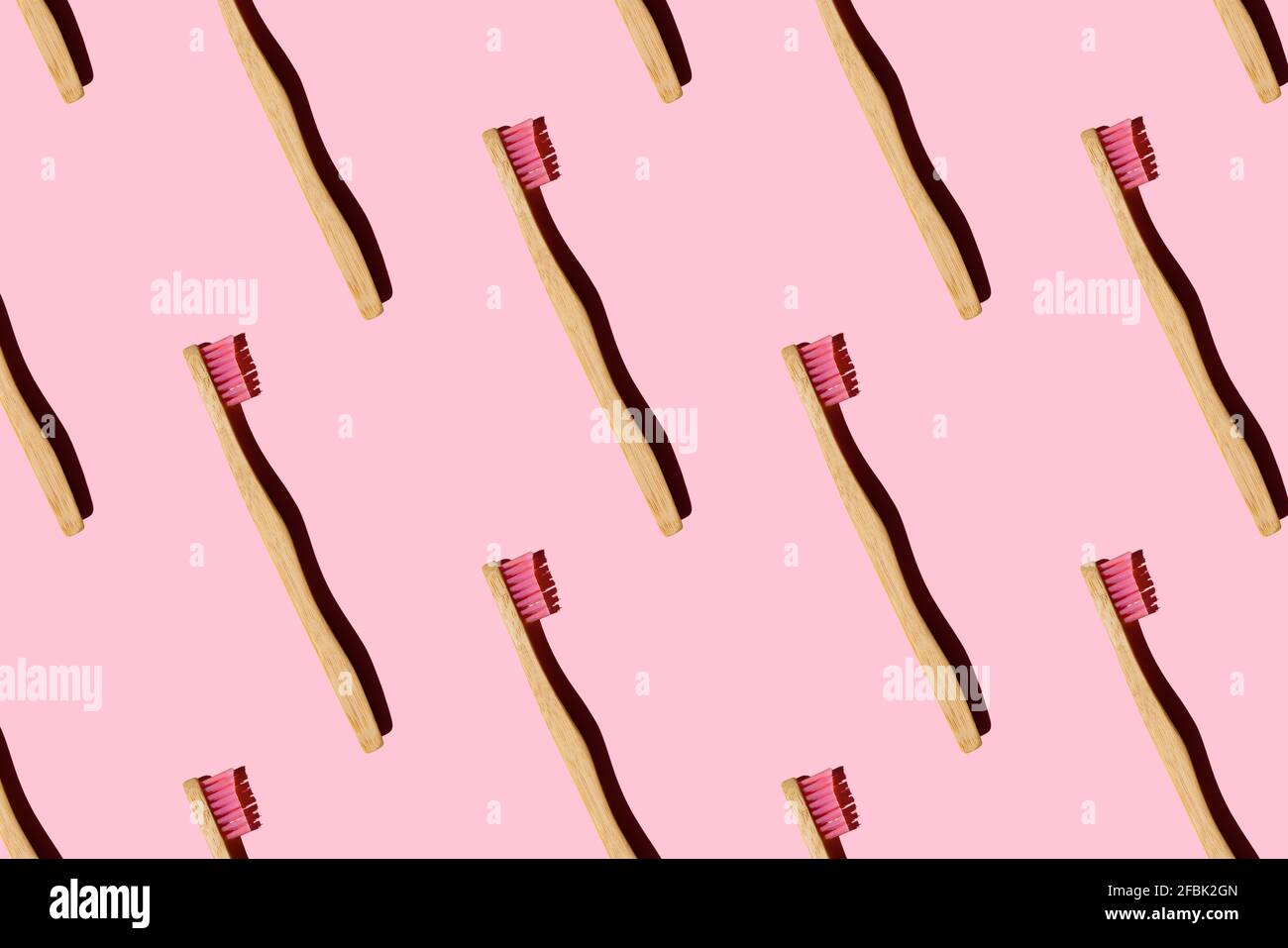 Digital generiertes Muster mit Bambuszahnbürsten auf rosa Hintergrund Stockfoto