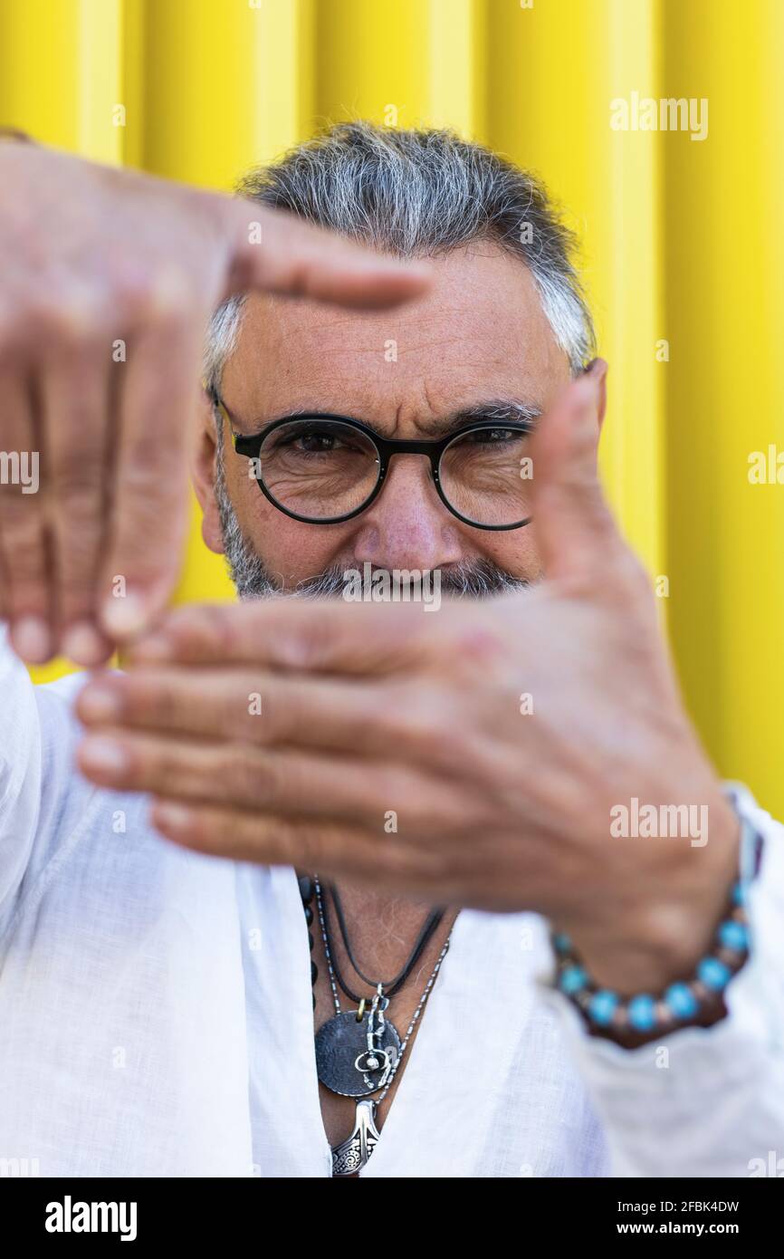 Reifer Mann, der durch den Fingerrahmen schaut Stockfoto