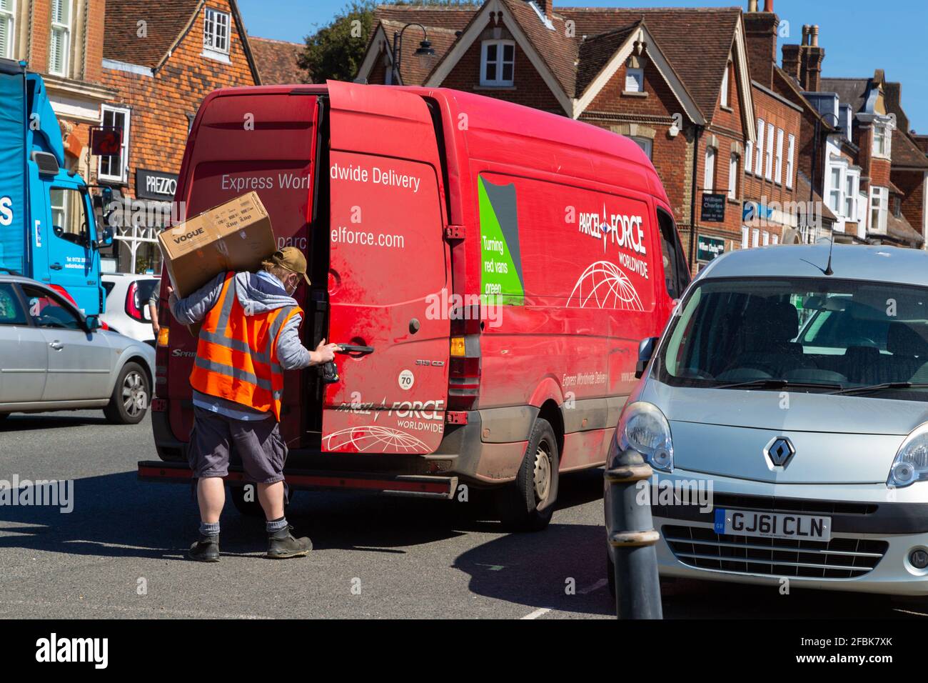 Paketdienst-Fahrer mit großem Paket auf der Schulter, tenterden High Street, kent, großbritannien Stockfoto