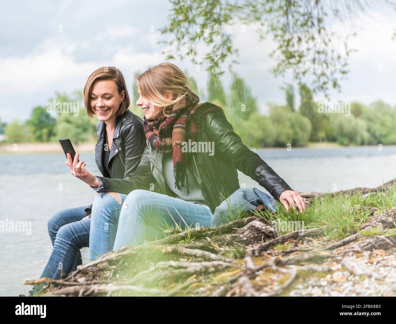 Zwei Freunde, die sich in der Natur entspannen und das Handy betrachten Stockfoto
