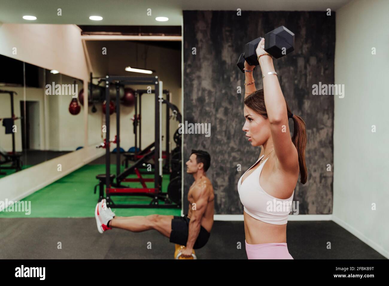Männliche und weibliche Sportler trainieren mit Geräten im Fitnessstudio Stockfoto