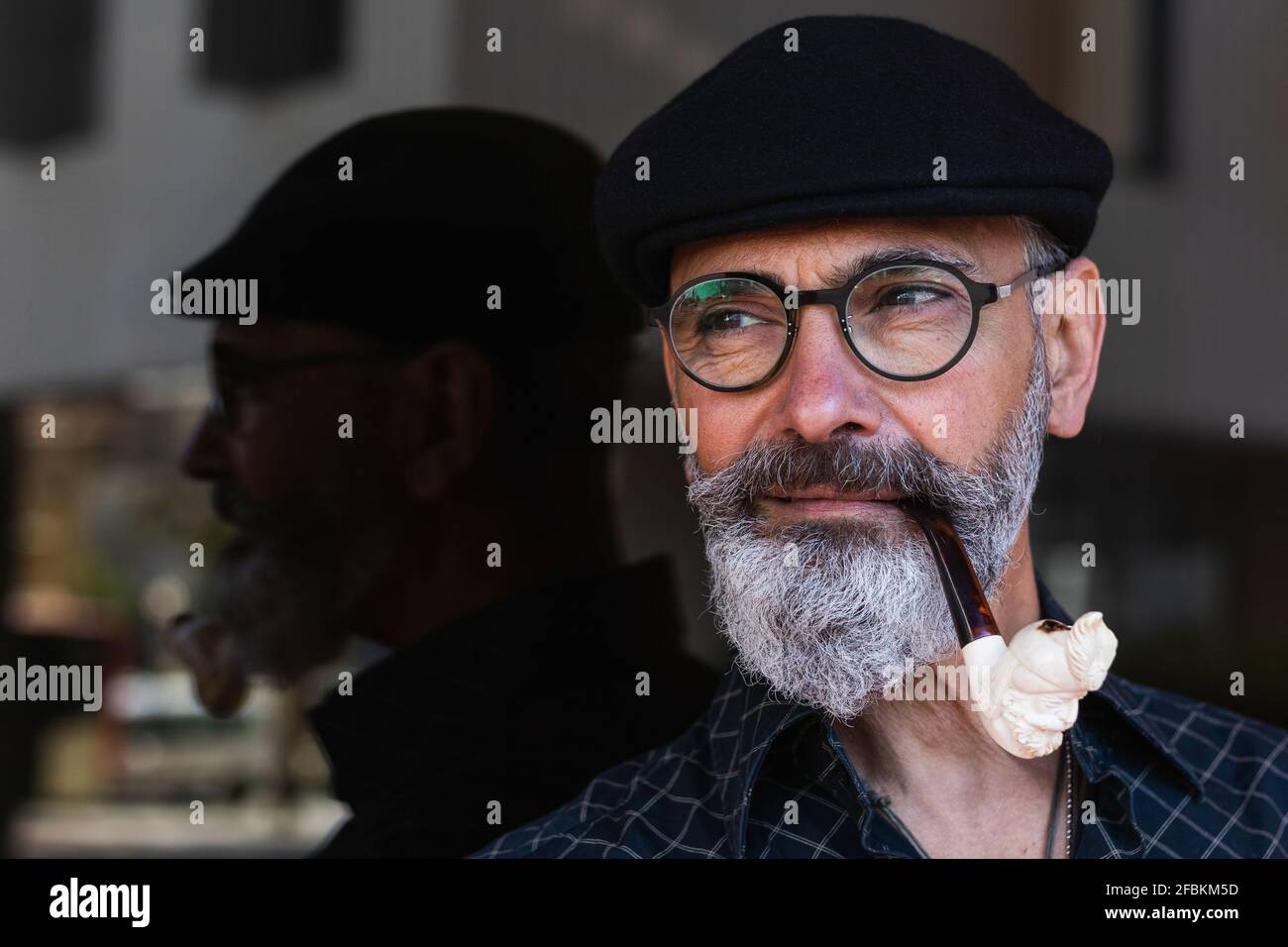 Reifer Mann, der Pfeife raucht und wegschaut Stockfoto