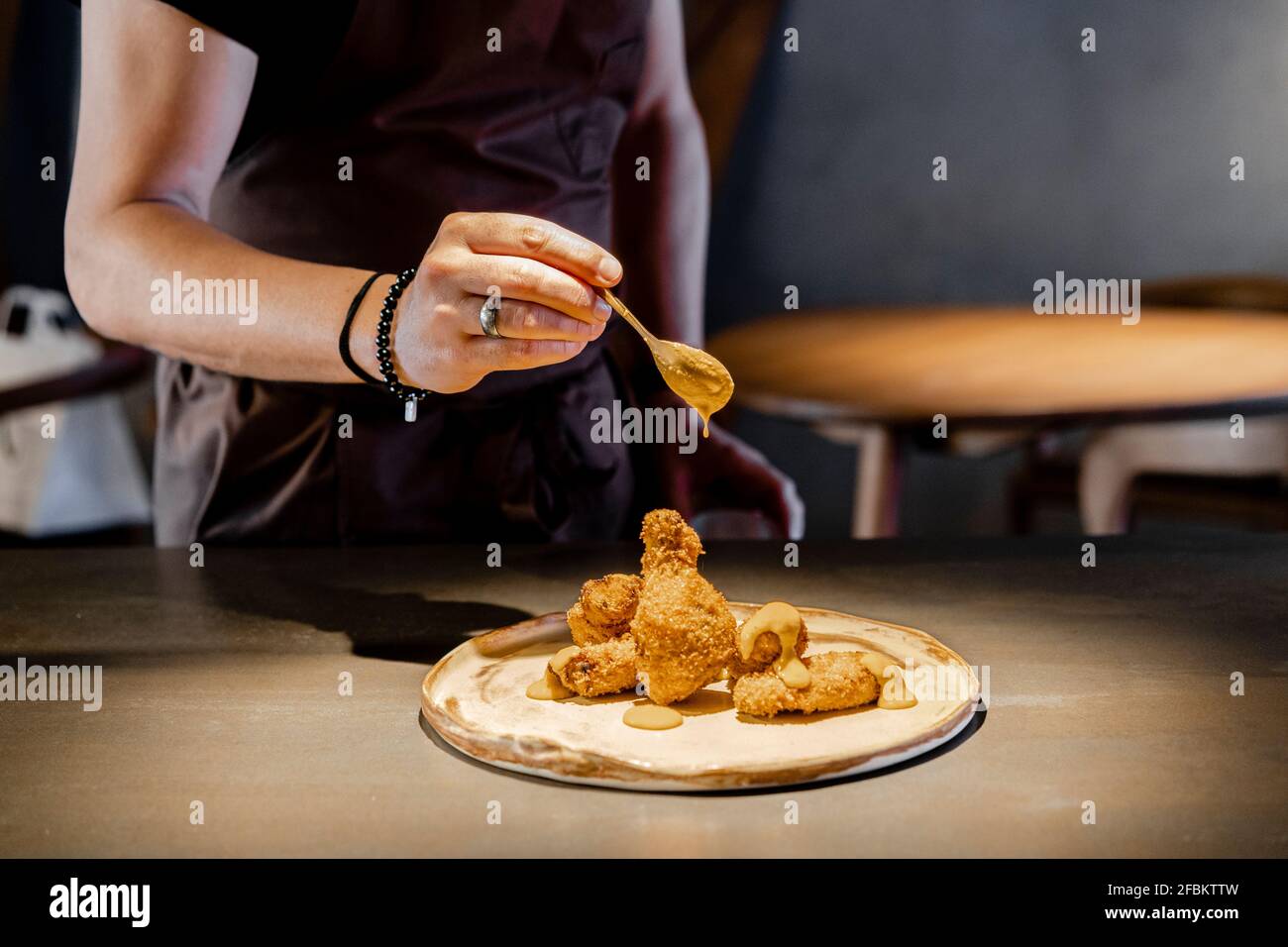 Männliche Expertise Gießen Sauce auf Huhn Nugget im Restaurant Stockfoto