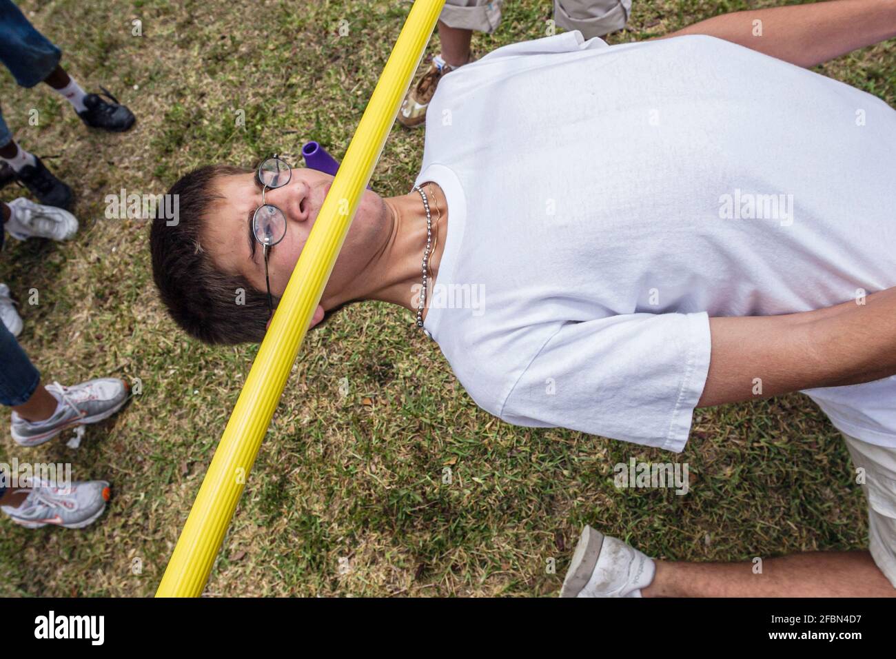 Miami Florida, Tropical Park Drug Free Youth in Town DFYIT, Teenager-Student Anti-Suchtgruppe Picknick, Hispanic Boy Limbo Contest lehnte Anstrengung unter Bar Stockfoto