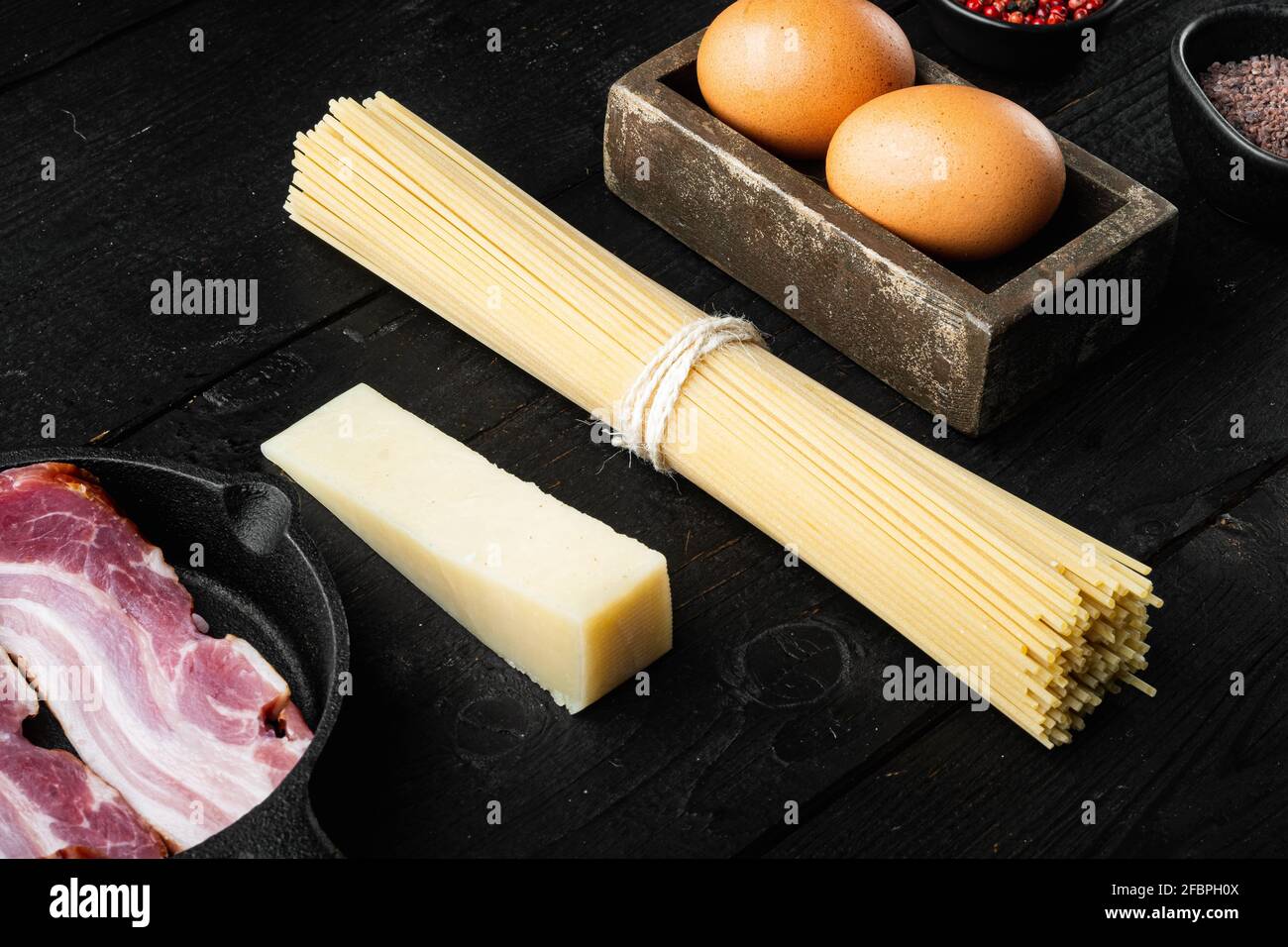 Traditionelle Italienische Pasta Carbonara Zutaten. Speck, Spaghetti, Parmesan und Pecorino-Käse, Ei, Knoblauch-Set, auf schwarzem Holzhintergrund Stockfoto