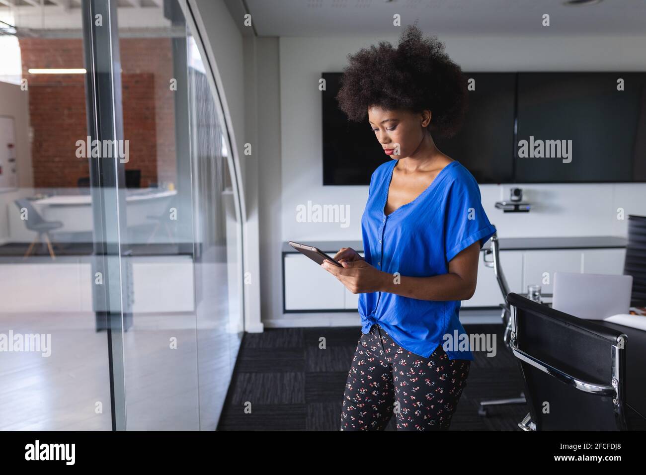 afroamerikanische Geschäftsfrau im Besprechungsraum stehend und im Einsatz Tablet Stockfoto