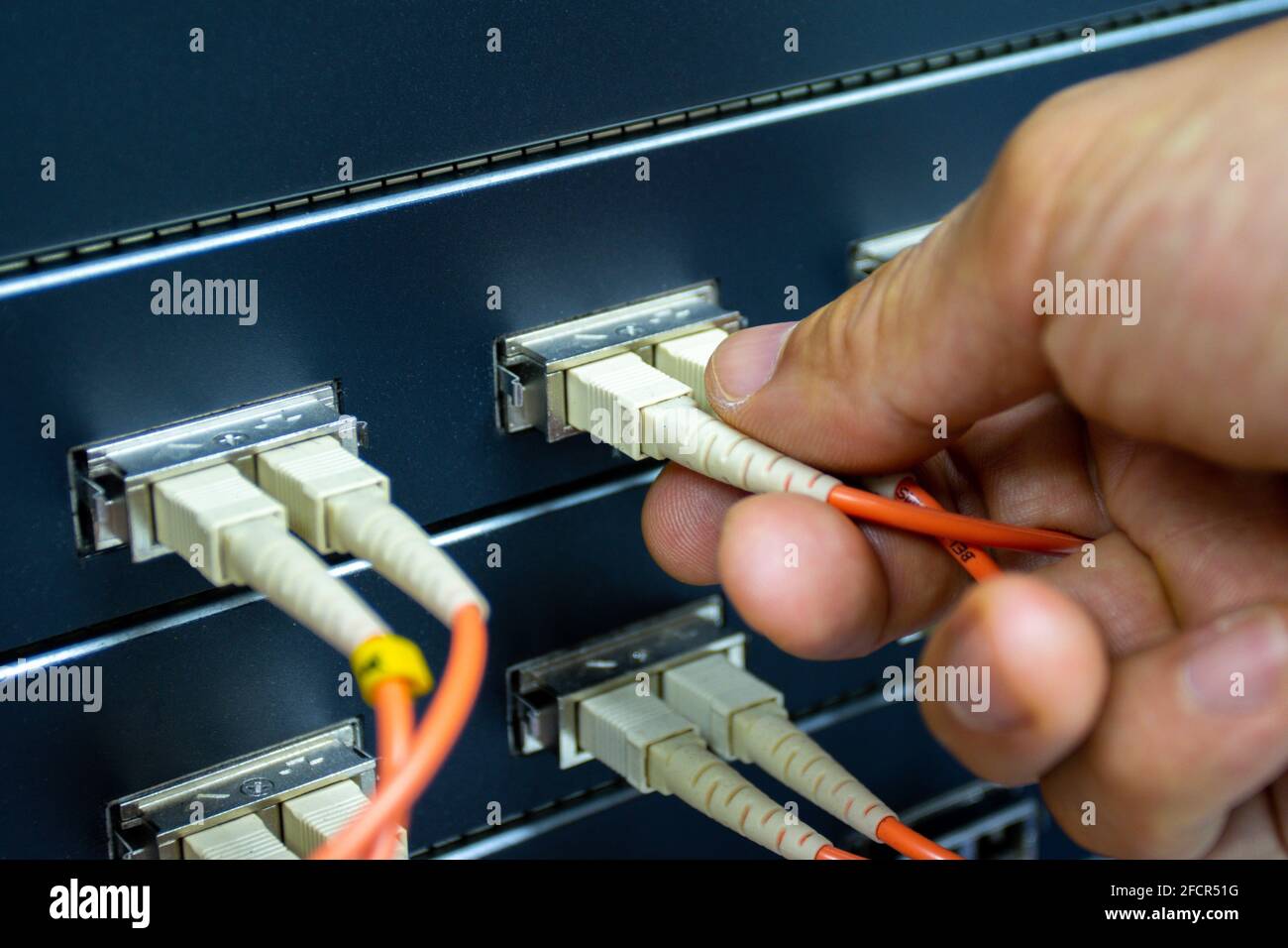 Techniker verbinden Glasfaserkabel mit Switch-Port im Serverraum, Konzept Internet-Netzwerk-Management Stockfoto