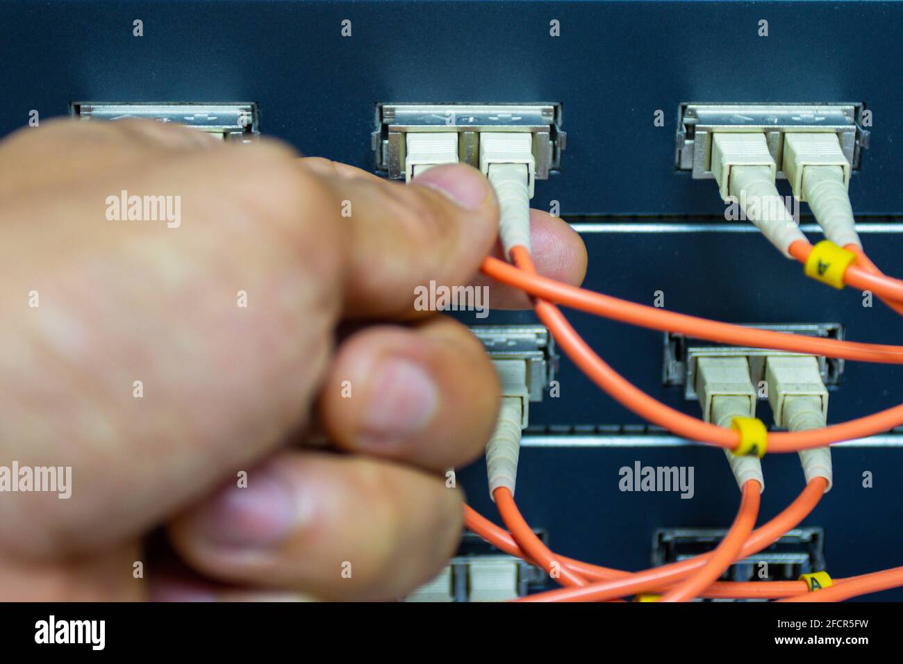 Techniker verbinden Glasfaserkabel mit Switch-Port im Serverraum, Konzept Internet-Netzwerk-Management Stockfoto